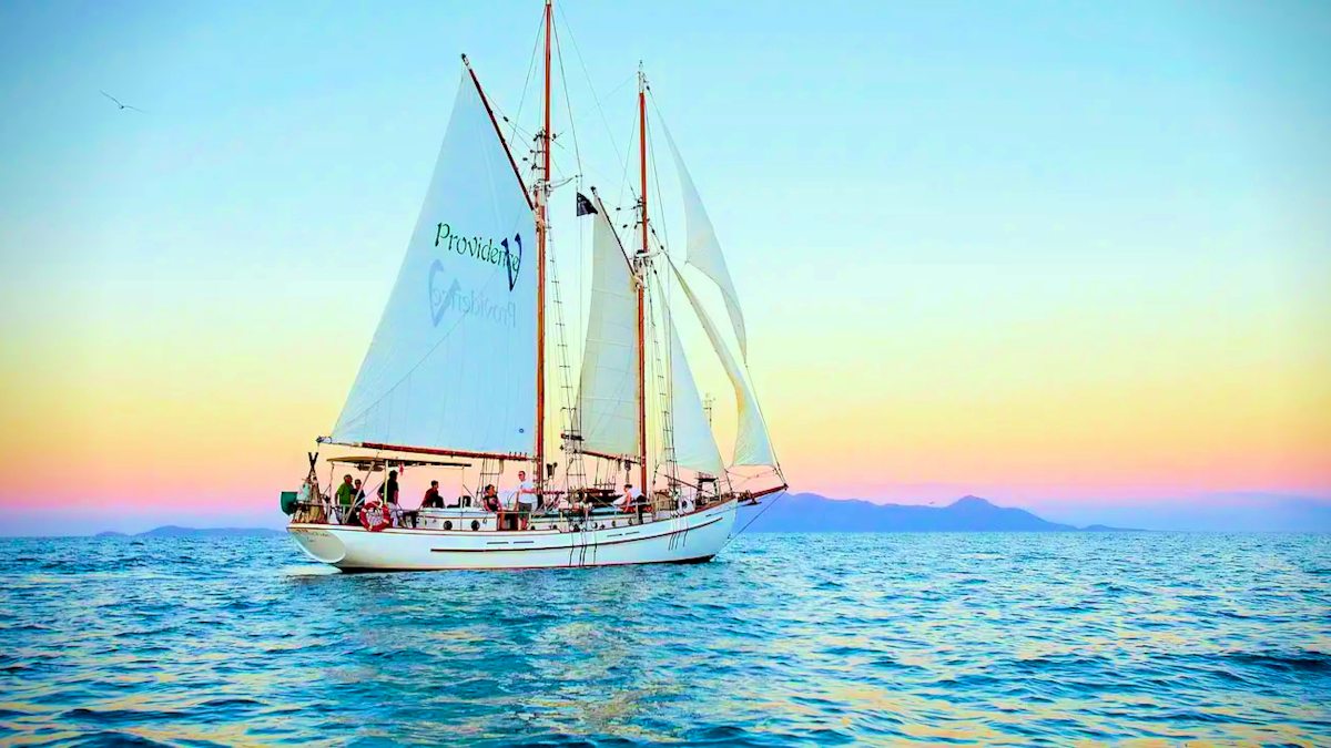 Sailing boat on the ocean - Whitsundays Tour - while the sun is going down. Colour scenery.